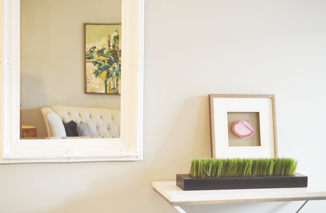 A beautifully styled living room featuring a large mirror, abstract painting, and minimalistic decor.